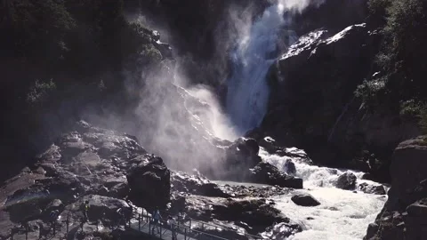 Aerial view - Backlight alpine waterfalls with a bridge over it and trekkers Stock Footage 137335324