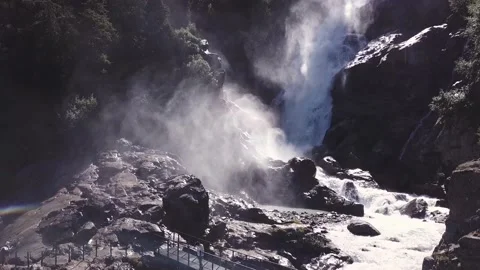 Aerial view - Backlight alpine waterfalls with a bridge over it and trekkers Stock Footage 137349289