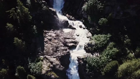 Aerial view - Backlight alpine waterfalls with a bridge over it and trekkers Stock Footage 137349319