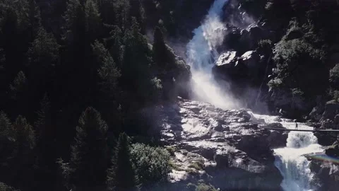 Aerial view - Backlight alpine waterfalls with a bridge over it and trekkers Stock Footage 137394283
