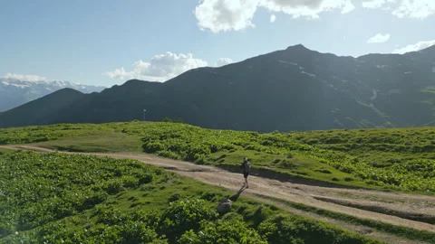 Aerial view of backpacker hiking in alpine meadows. Person walking along dirt Stock Footage 280291960