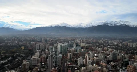 Aerial view of a backward pan of a city with its buildings and the Andes Moun Stock Footage 156567302