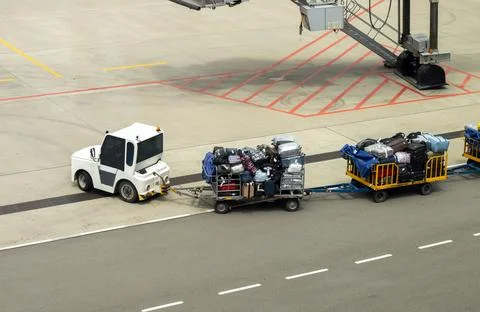 Aerial view of baggage tractor pulls baggage carts with passengers' luggage t Stock Photos