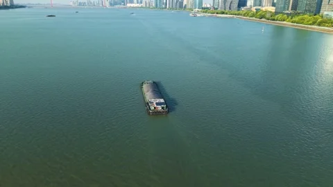 Aerial view of barge navigates river in urban setting with modern skyscrapers 動画素材 311558366