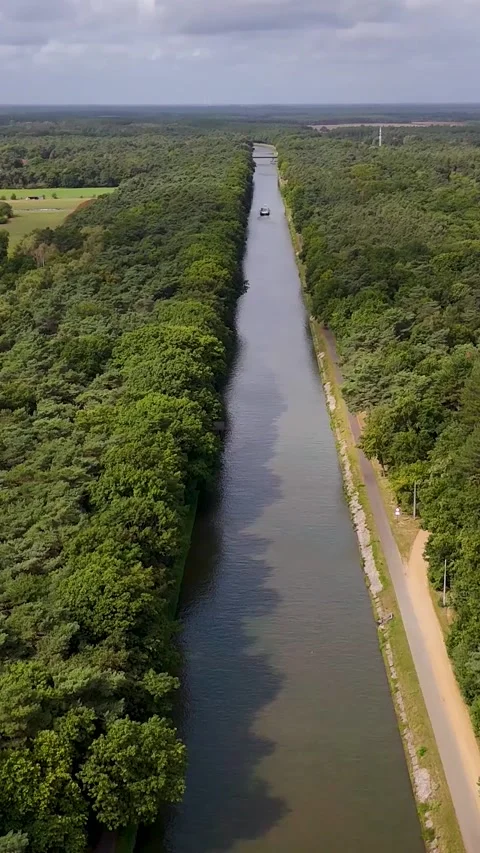 Aerial view of barge navigating canal through green forest Видео 327110686
