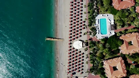 Aerial View of Beach with Red Umbrellas and Wooden Pier Stock Footage 296515097