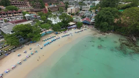 Aerial view of beach with umbrellas, clear water, and coastal buildings 스톡 동영상 342333381