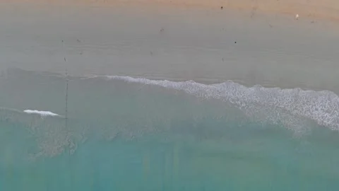 Aerial view of beach waves gently rolling onto sandy shore at sunset Vídeo Stock 337417905