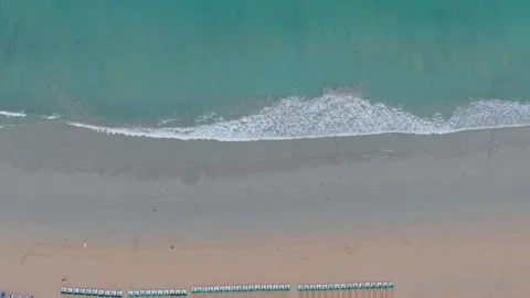 Aerial view of beach with waves lapping against sandy shore and sunbeds Stock Footage 336926862