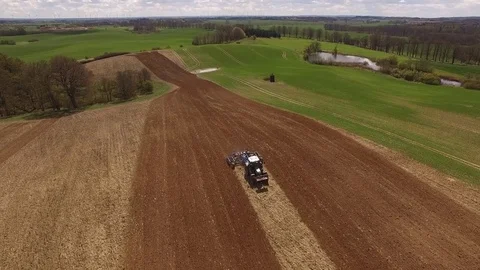 Aerial view of beautiful agricultural fields with a tractor cultivating a field Stock Footage 74988728