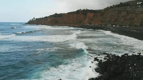 Aerial view. Beautiful waves of turquoise color fall on the coast with black Video stock 112032310