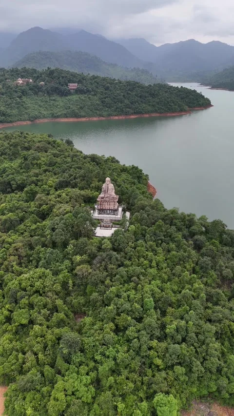 Aerial View of Big Buddha Statue in a Forest Peninsula by a Lake in Hue, Vietnam Stock Footage 335835706