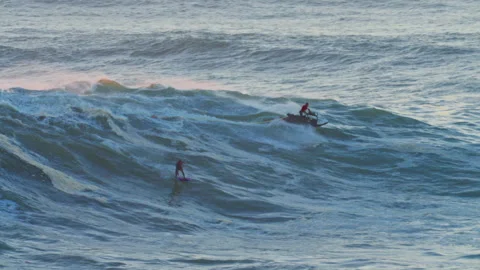 Aerial view of a big wave surferwith accompaniment on a big wave in Nazare Stock Footage 311244811
