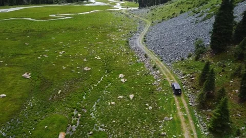 Aerial View of Black SUV Driving by Massive Mountain Rock Field Video stock 332010345