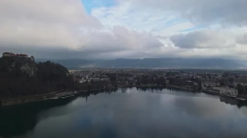 Aerial view of Bled Castle above Lake Bled with winter clouds over the Alps Stock Footage 336467645