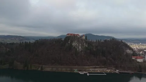 Aerial view of Bled Castle on a cliff above Lake Bled with winter mountains Stock Footage 336467636