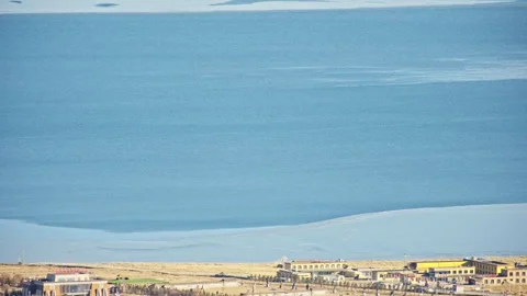Aerial View of Blue Ocean with Floating Ice and Small Town Stock Footage 326415247