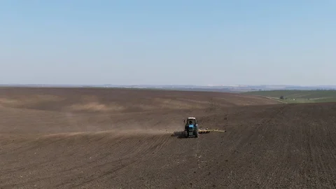Aerial view blue tractor with a seeder goes across the field. Stock Footage 128368399