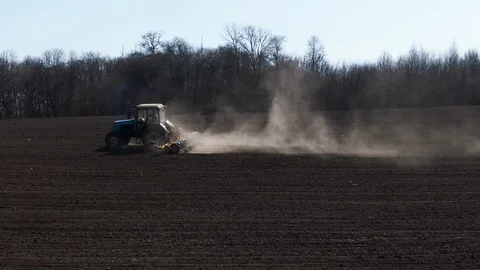 Aerial view blue tractor with a seeder goes across the field. Video stock 128368418