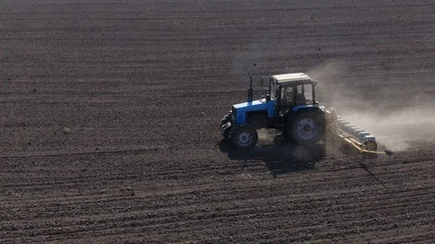 Aerial view blue tractor with a seeder goes across the field. Video stock 128368586