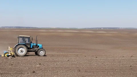 Aerial view blue tractor with a seeder goes across the field. Stock Footage 128368810