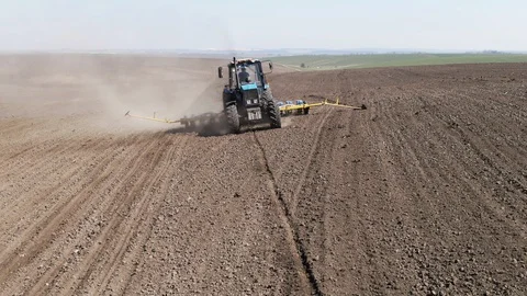 Aerial view blue tractor with a seeder goes across the field. Video stock 128368938