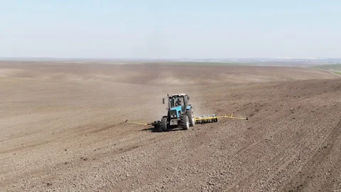 Aerial view blue tractor with a seeder goes across the field. Stock-Footage 128369253