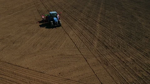 Aerial view of a blue tractor seeding corn on a big farm field Stock Footage 89524724