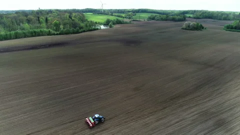 Aerial view of a blue tractor seeding corn on a big farm field Stock Footage 89527046