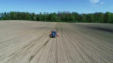 Aerial view of a blue tractor seeding corn on a big farm field Stock Footage 89531077