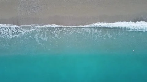Aerial view of blue waves splashing on seashell beach shore Stock Footage 312898615