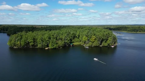 Aerial View of a Boat Approaching a Forested Cove on a Lake Stock-Footage 338324882