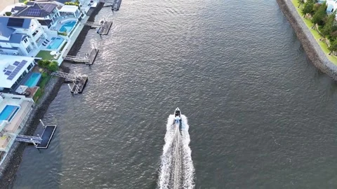Aerial view of a boat creating a wake in a canal with luxury homes and priv.. Vídeo Stock 332709426