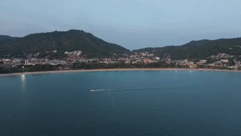 Aerial view of boat moving across calm water near coastal town at dusk Video stock 342331653