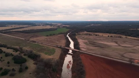 Aerial View of Bridge Crossing River Between Red Earth and Winter Farmland Stock Footage 322205209