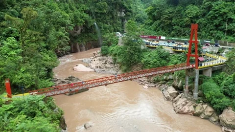 Aerial view of a bridge in the jungle surrounded by a river and mountains. Video stock 135369594