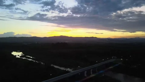 Aerial View of Bridge Over River at Sunset with Mountain Silhouette Stock Footage 308228884