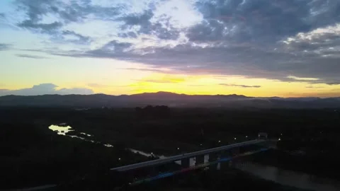Aerial View of Bridge Over River at Sunset with Mountain Silhouette Stock Footage 308228904