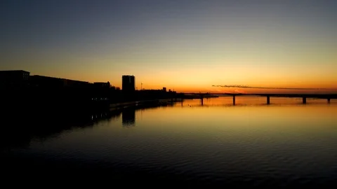 Aerial view of Bridge over a wide river at sunset.The sunset is reflected in the Stock Footage 117779013