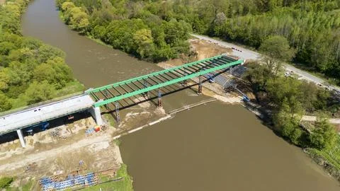 Aerial view of a bridge under construction over a river surrounded by lush Stock Photos