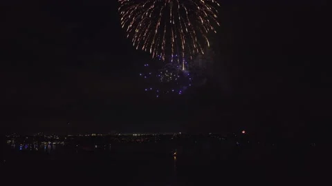 Aerial view of bright fireworks exploding with colorful lights over sea shore on Stock Footage 208532206