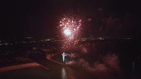 Aerial view of bright fireworks exploding with colorful lights over sea shore on Stock Footage 228049442