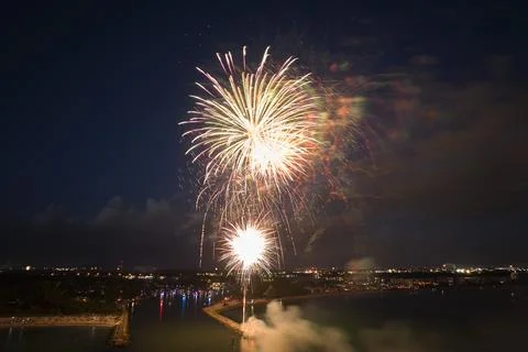 Aerial view of bright fireworks exploding with colorful lights over sea shore on Stock Photos