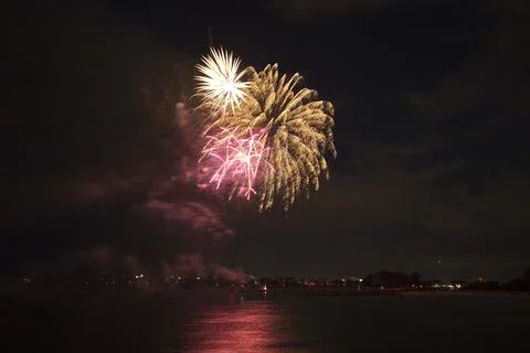 Aerial view of bright fireworks exploding with colorful lights over sea shore on Stock Photos