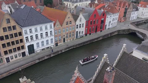 Aerial view of Bruges triangular rooftops and tourist boat on canal. Stock Footage 328618627