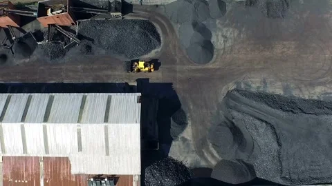 Aerial view of bulldozer operating inside open coal storage depot with large Stock Footage 333719814