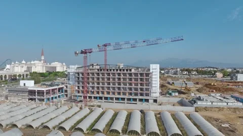 Aerial View: A bustling construction site with cranes lifting materials and Stock Footage 296150718