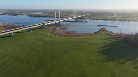 Aerial view of a cable stayed bridge over a wide river with two cargo vessels Stock-Footage 329077419
