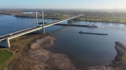 Aerial view of a cable stayed bridge spanning a wide river as two large vessels 库存影片 329077420