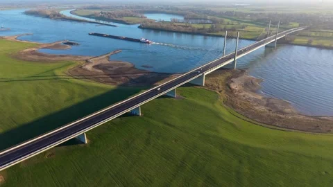 Aerial view of a cable stayed bridge spanning a wide river, with vehicles Stock Footage 329811171